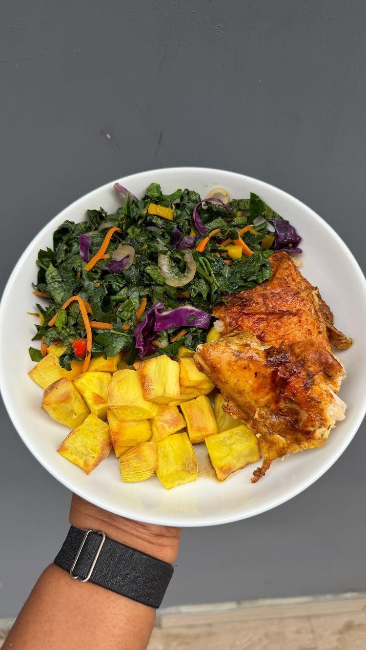 Plate of roasted chicken, yellow vegetables, and colorful leafy salad held in one hand