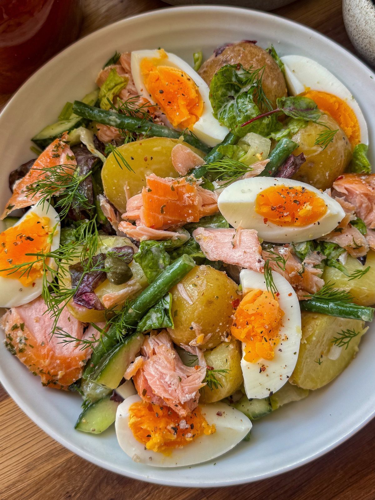 Salmon and egg salad with potatoes, green beans, cucumber, and fresh herbs