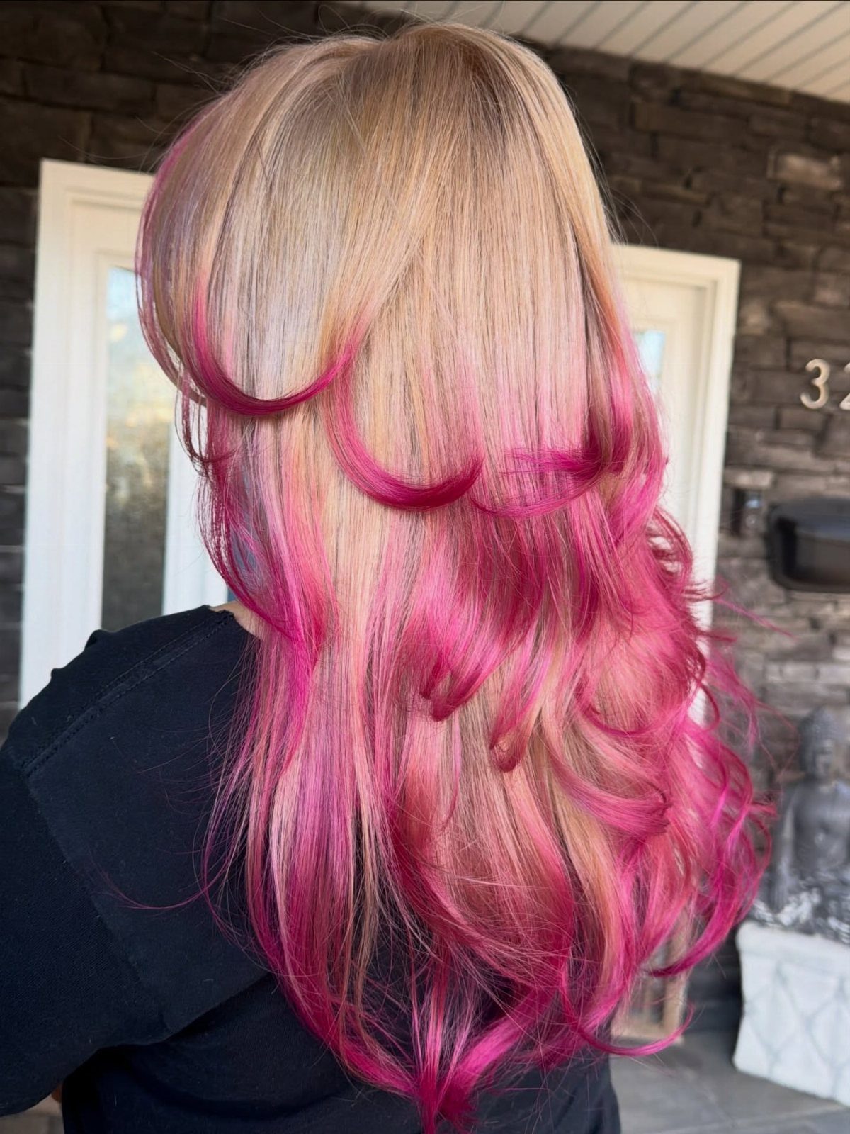 Blonde layered hair with vivid pink streaks and curled pink ends