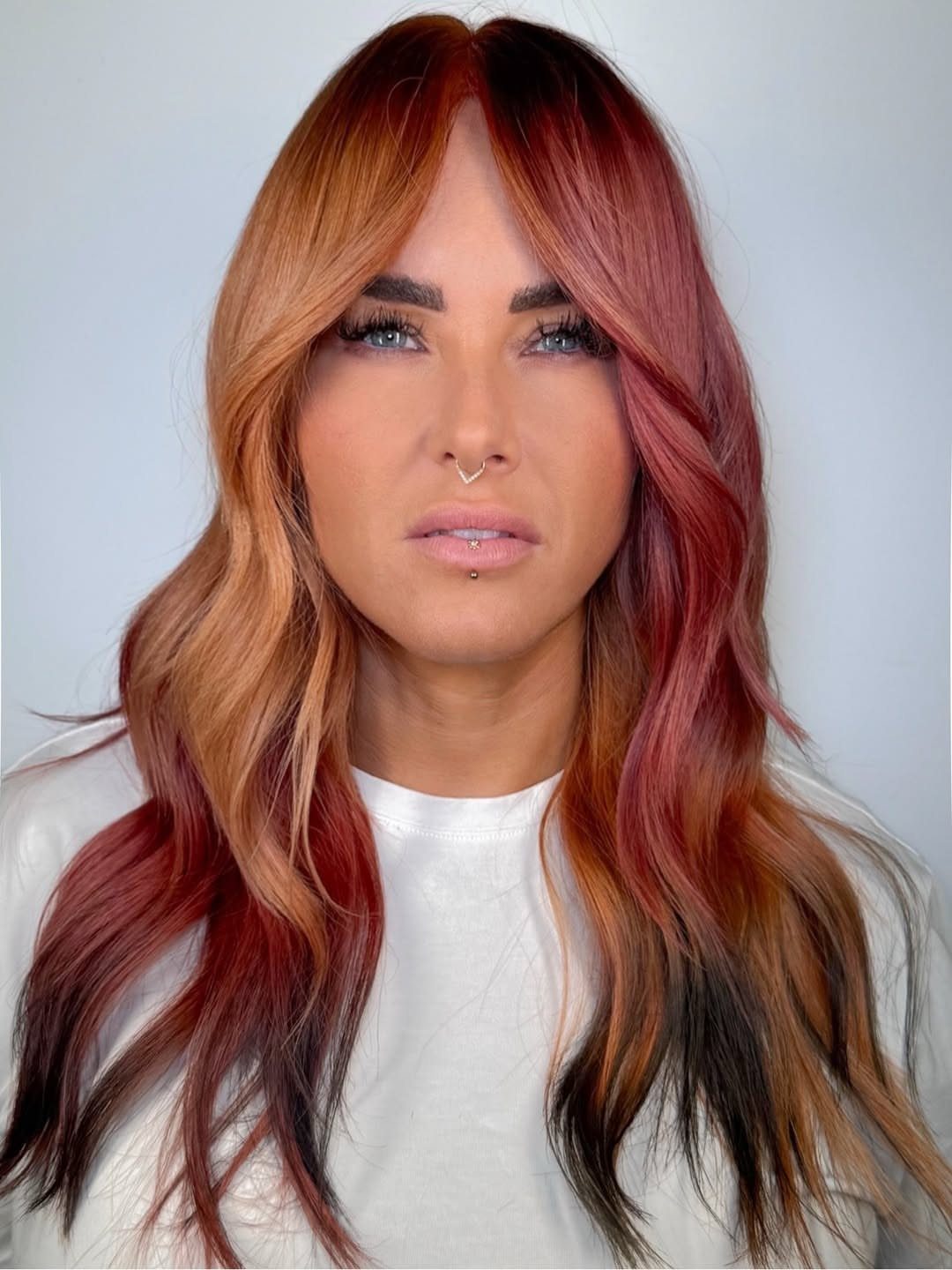 Woman with long wavy copper-orange hair fading through auburn into dark ends
