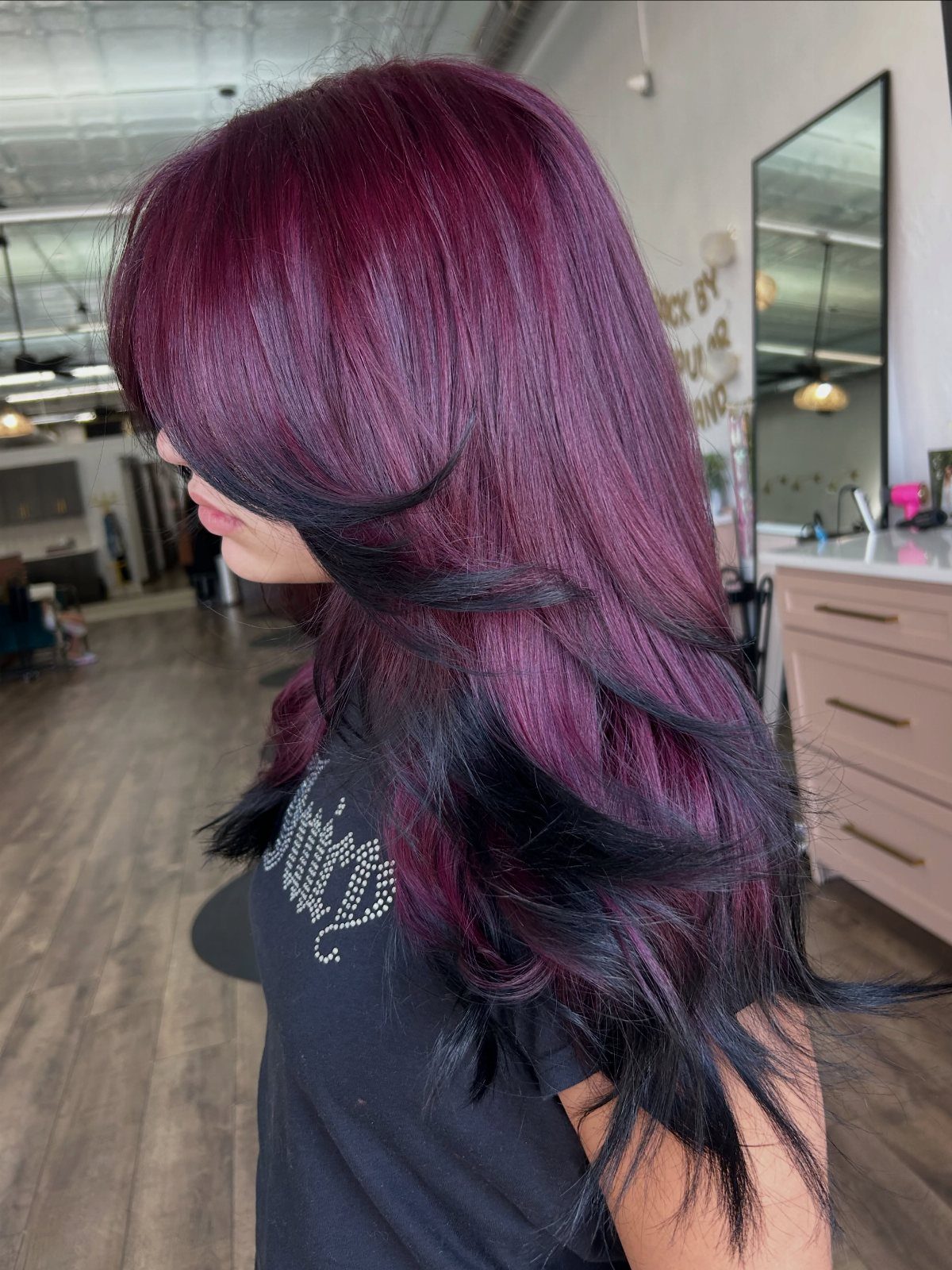 Long purple-magenta and black layered hair styled in loose curved ends