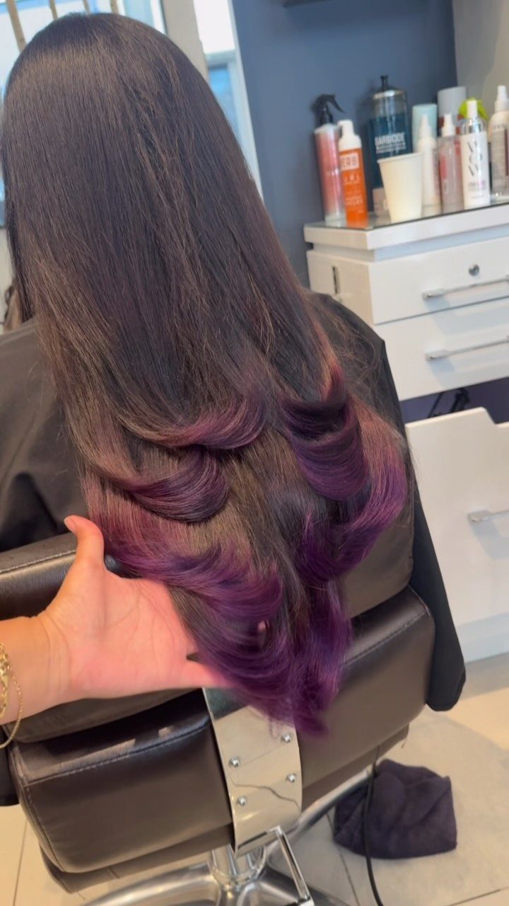 Dark layered hair with purple and magenta curled ends in a salon chair