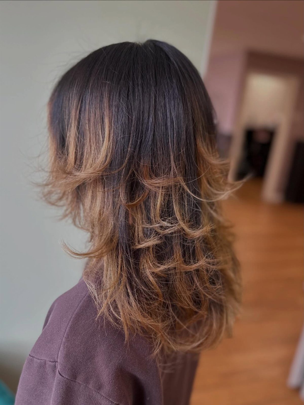 Shoulder-length dark hair with copper streaks and flipped, layered ends