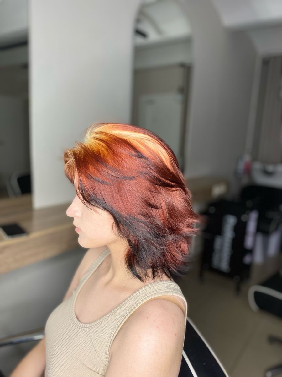 Short wavy hair with vivid copper-orange streaks and dark auburn layers
