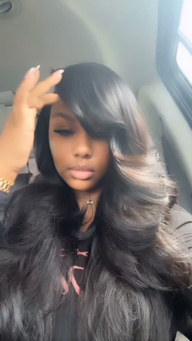 Woman poses with long, voluminous black hair styled in glossy waves