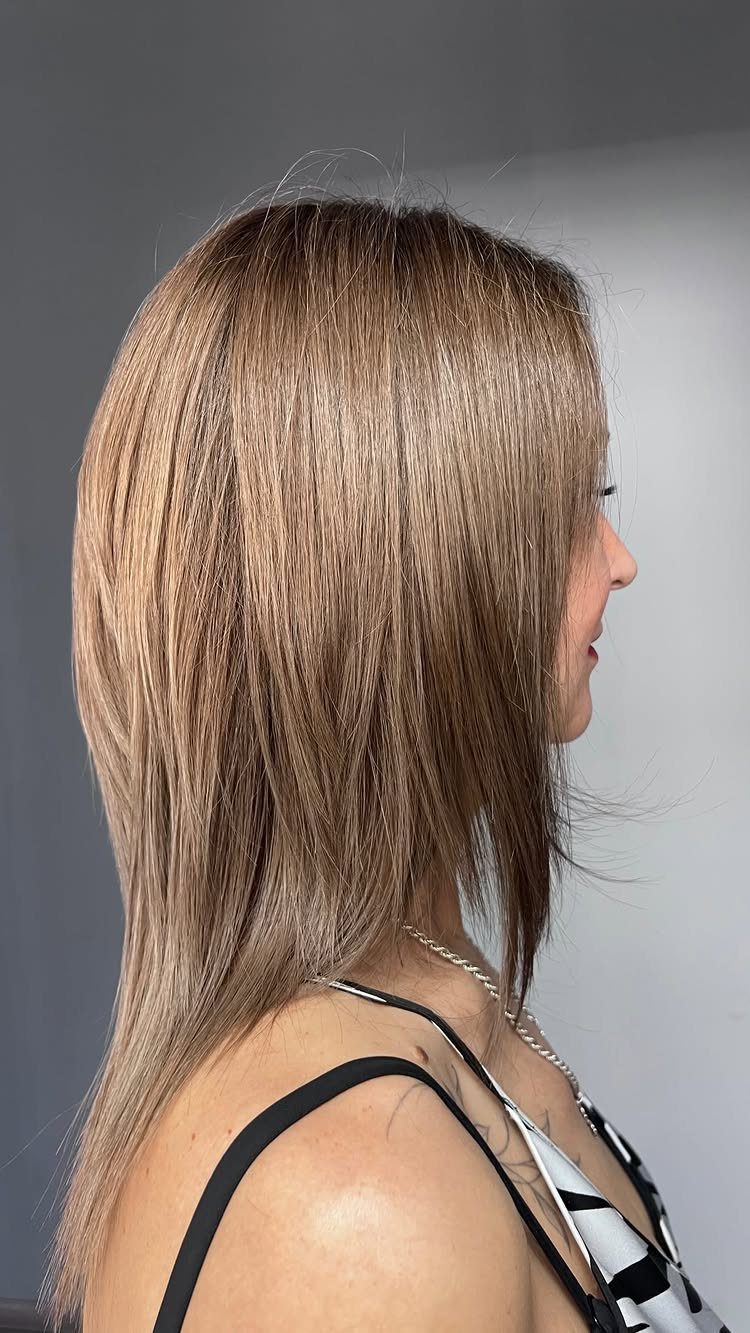 Woman displaying straight, layered light brown hair with long side-swept bangs