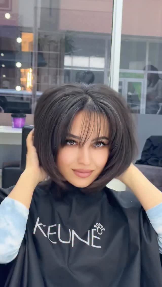 Woman poses in a salon showing a voluminous angled bob with wispy bangs