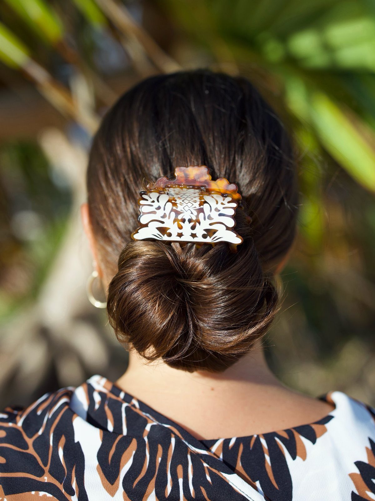 Dark hair twisted into a low bun and secured with an ornate claw clip