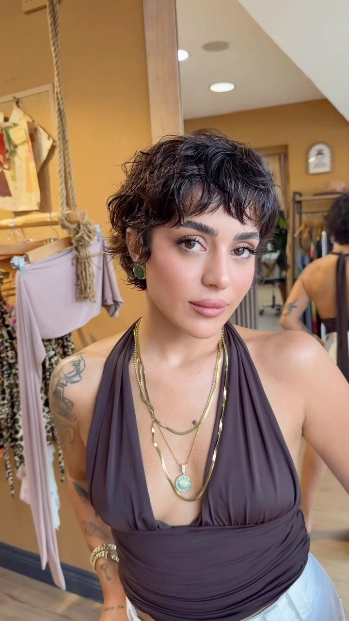 Woman with a short, tousled dark pixie cut and wispy bangs