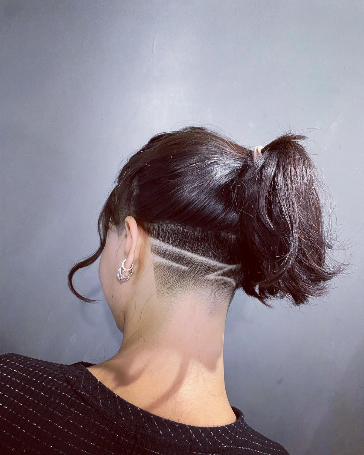 Shaved nape with curved lines beneath a dark ponytail