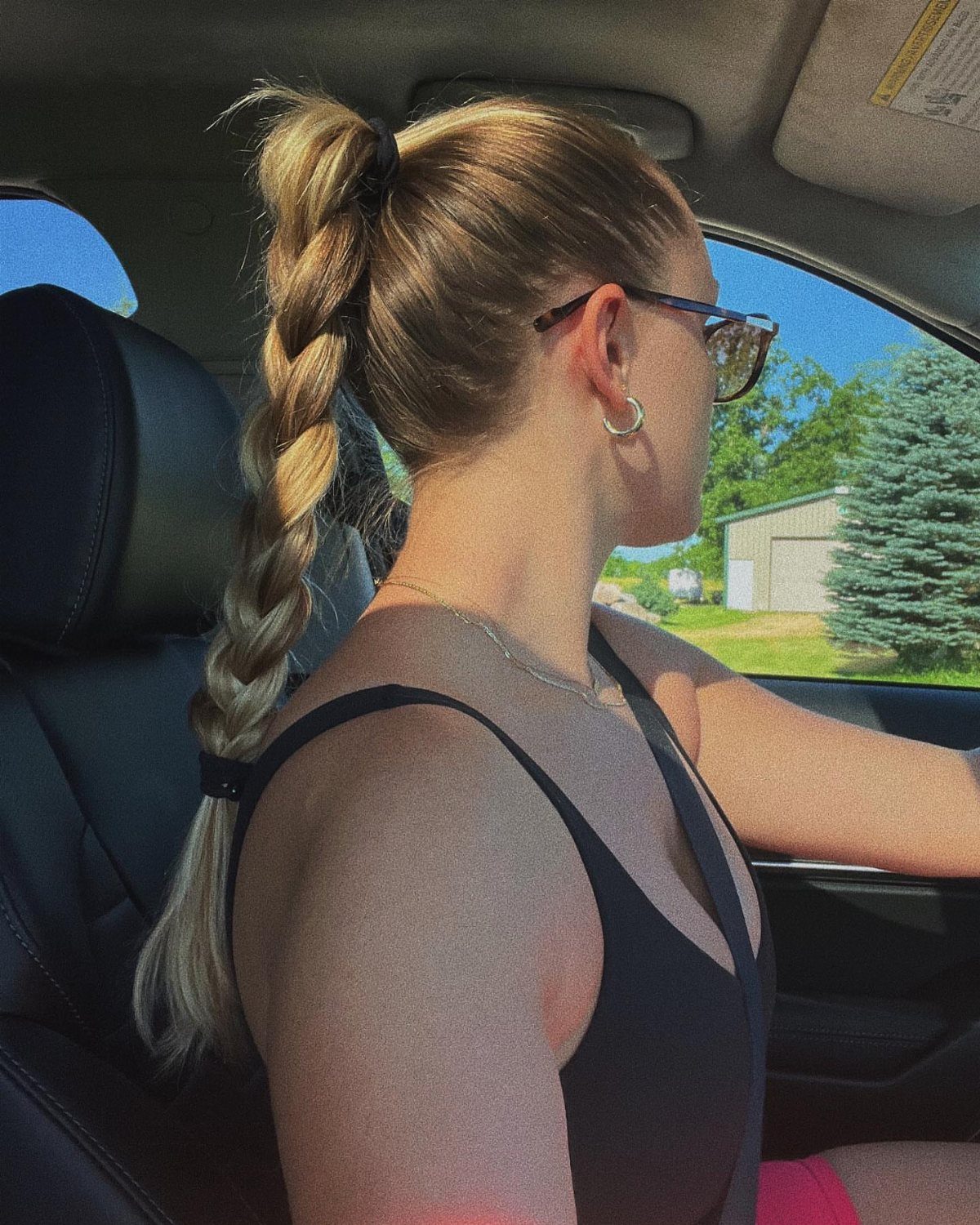 Woman drives wearing a long braided ponytail tied high at the back