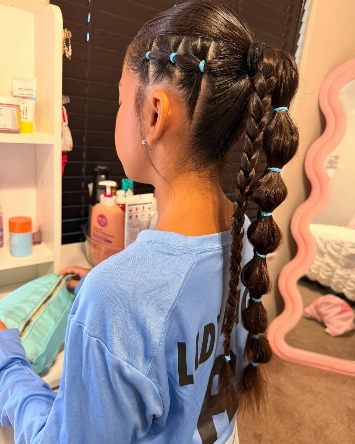 Dark hair in a high ponytail with rounded sections held by blue elastics