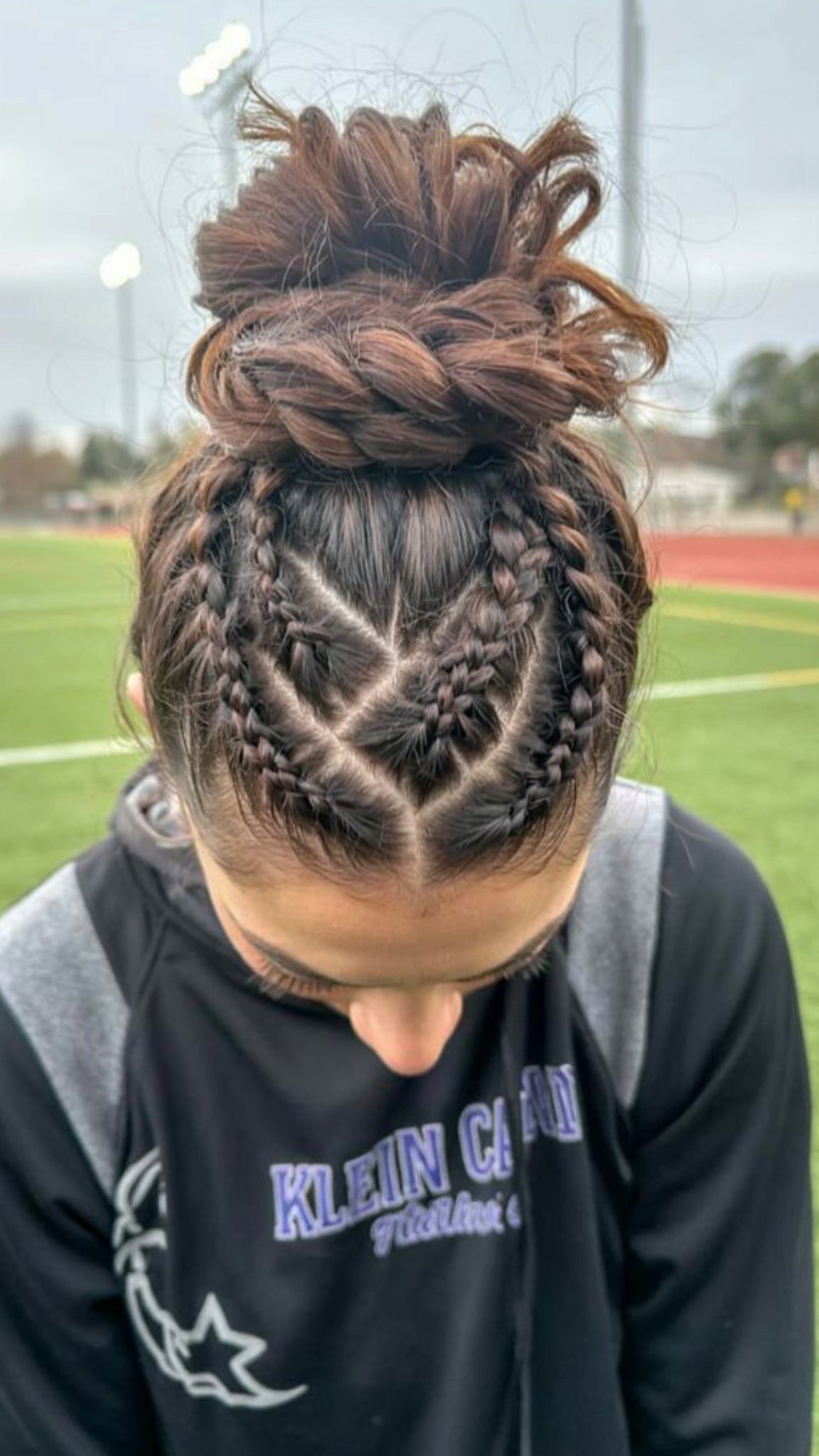 Cornrow braids form a geometric pattern beneath a high messy bun