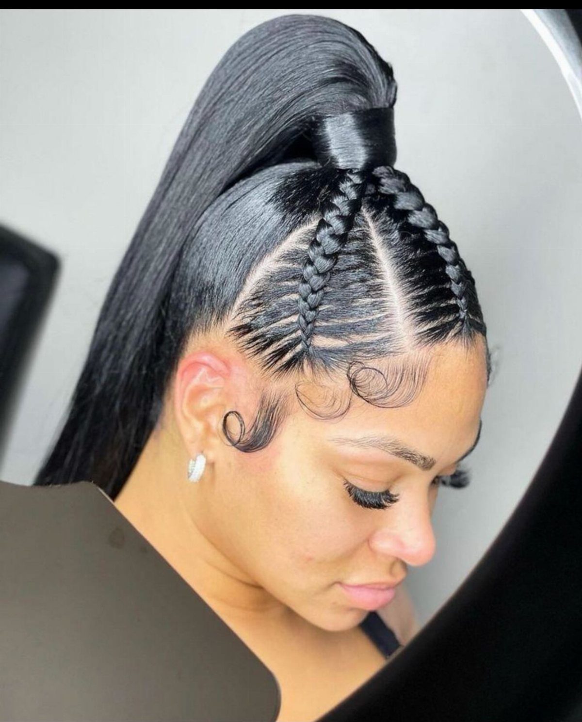 Tight cornrows feed into a sleek high ponytail with curled baby hairs