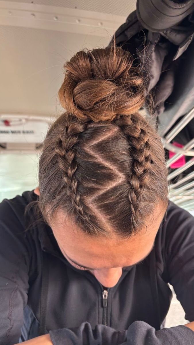 Curved French braids follow a zigzag part and meet beneath a high bun