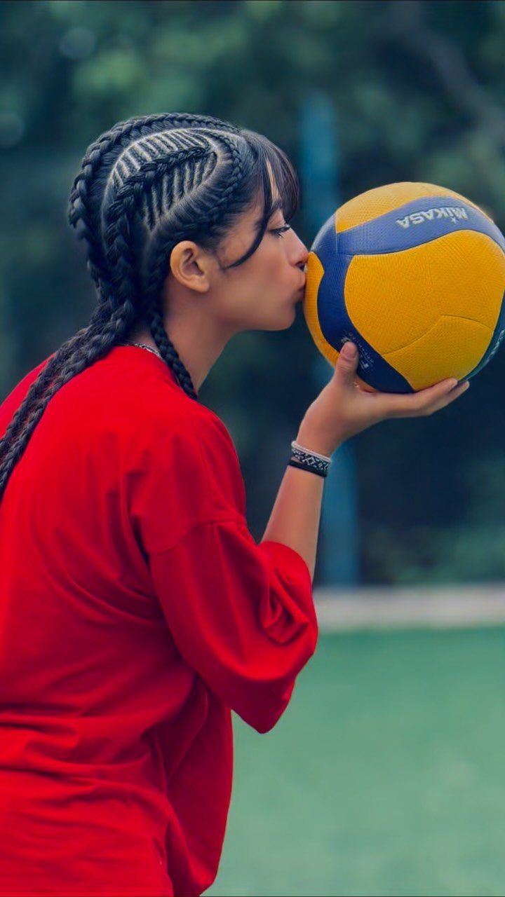 Dutch braids feed into a thick braid as a volleyball player holds a ball