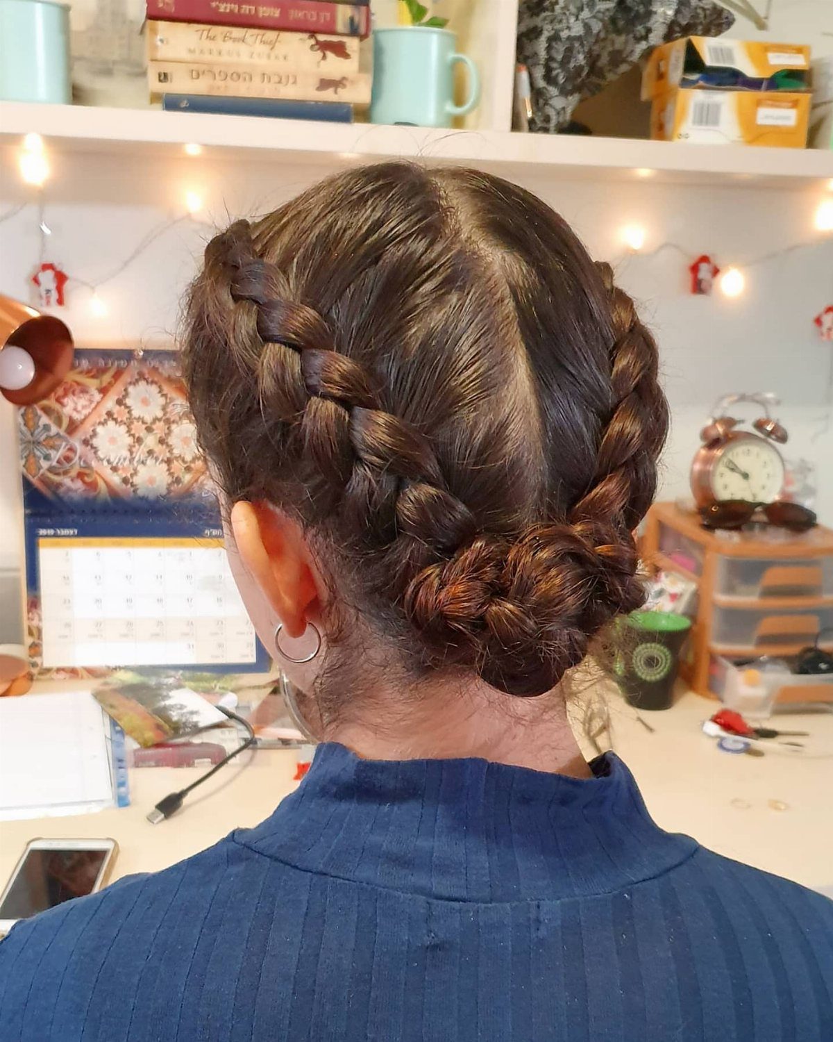 Two Dutch braids join into a low bun on the back of a woman's head.