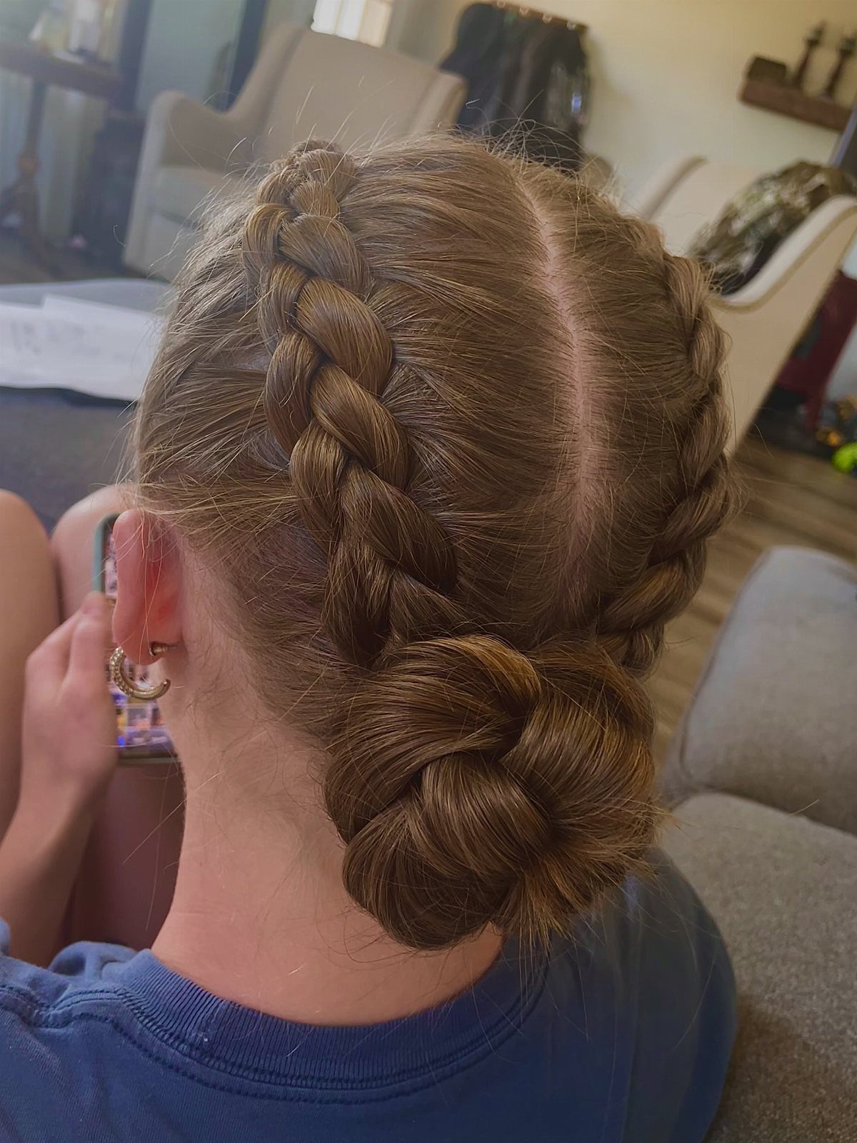 Two French braids feed into a low bun at the back of a person's head