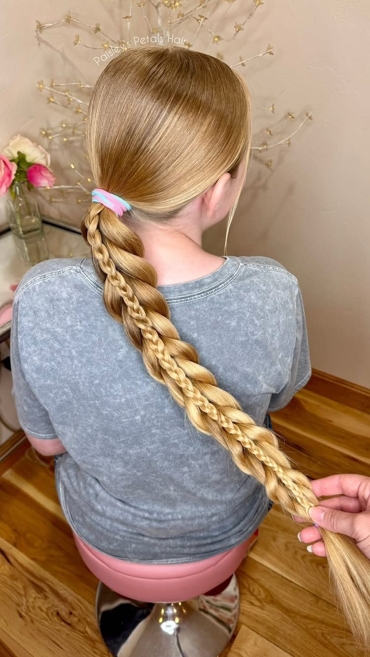 Long blonde pull-through braid held at the end while its wearer sits