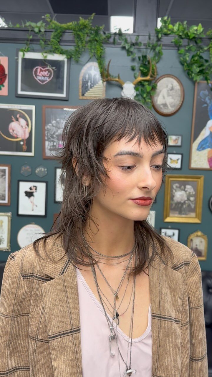 Person showing a choppy dark mullet with longer layers at the back