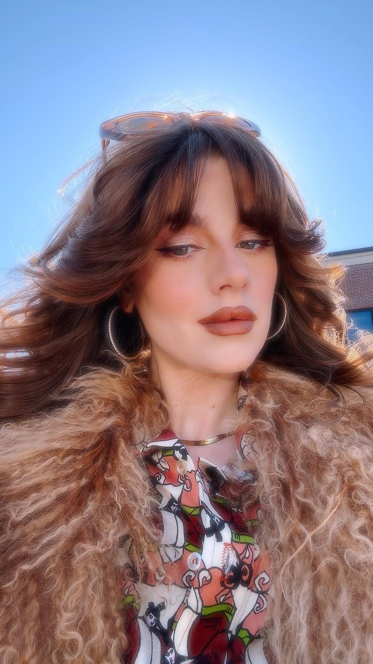 Woman with a shag haircut, layered brown hair, and feathered fringe