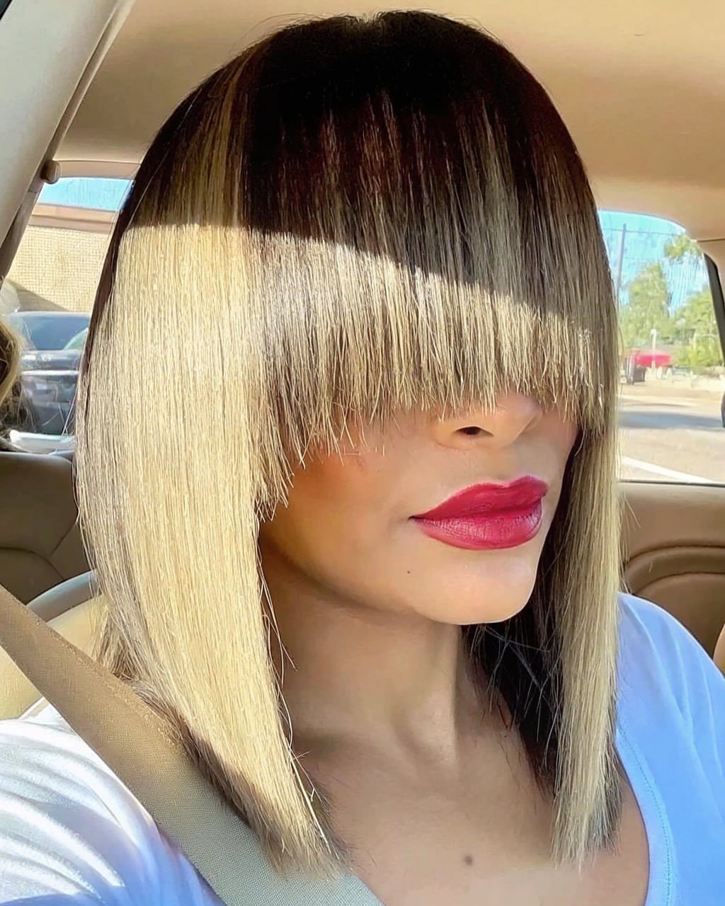 Woman with straight blonde hair and blunt bangs covering her eyes