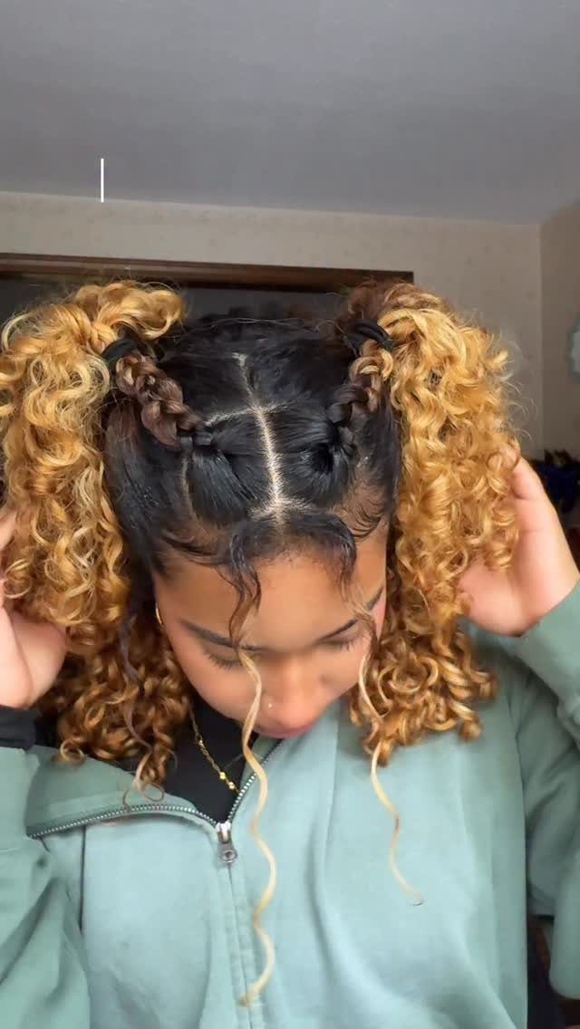Curly blonde pigtails with braided sections frame a person's face