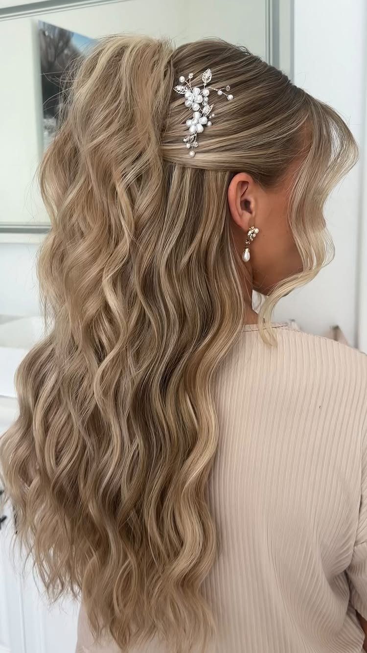 Long blonde half-up hair with loose waves and a sparkling floral clip