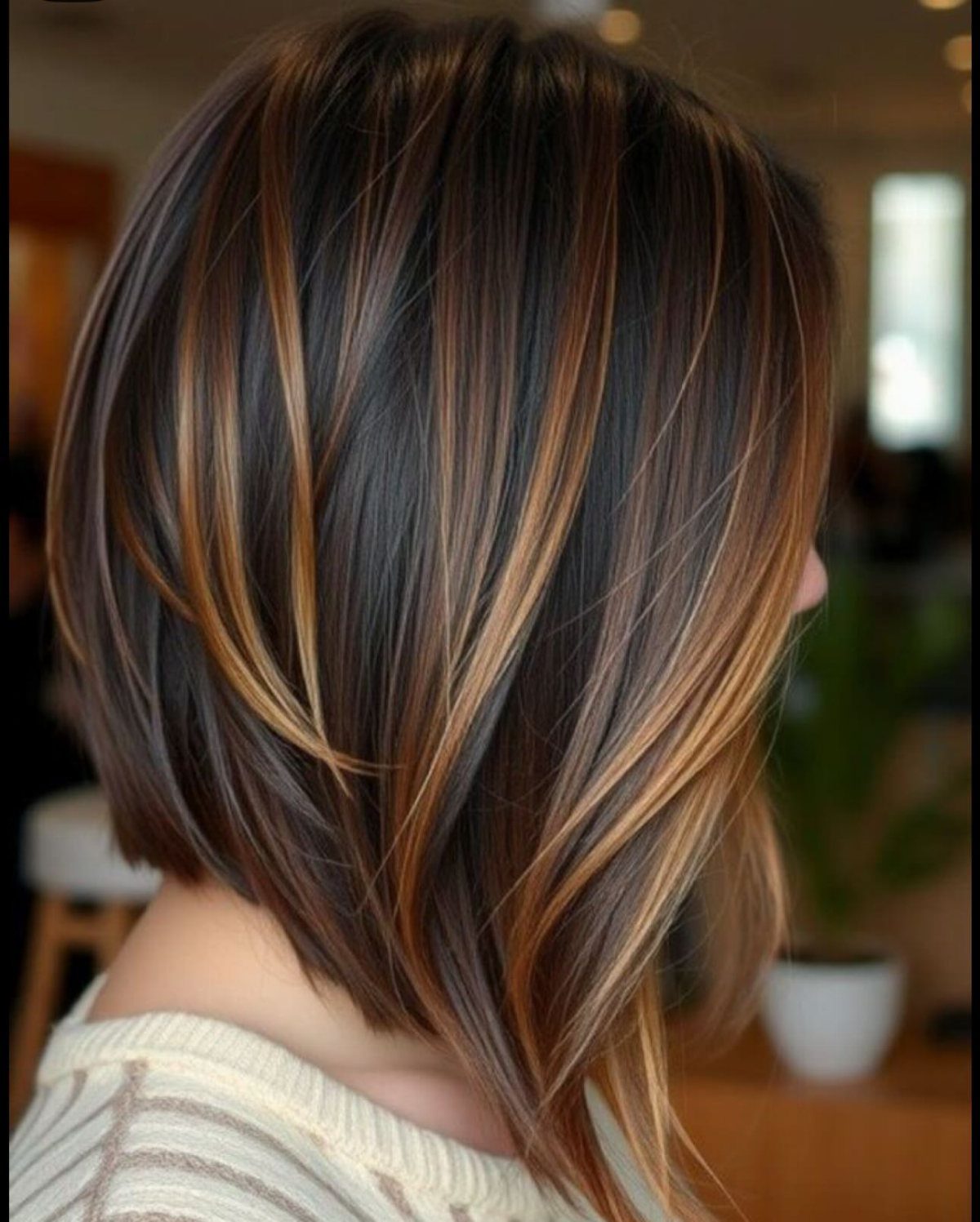 Layered shoulder-length bob with dark hair and caramel blonde highlights