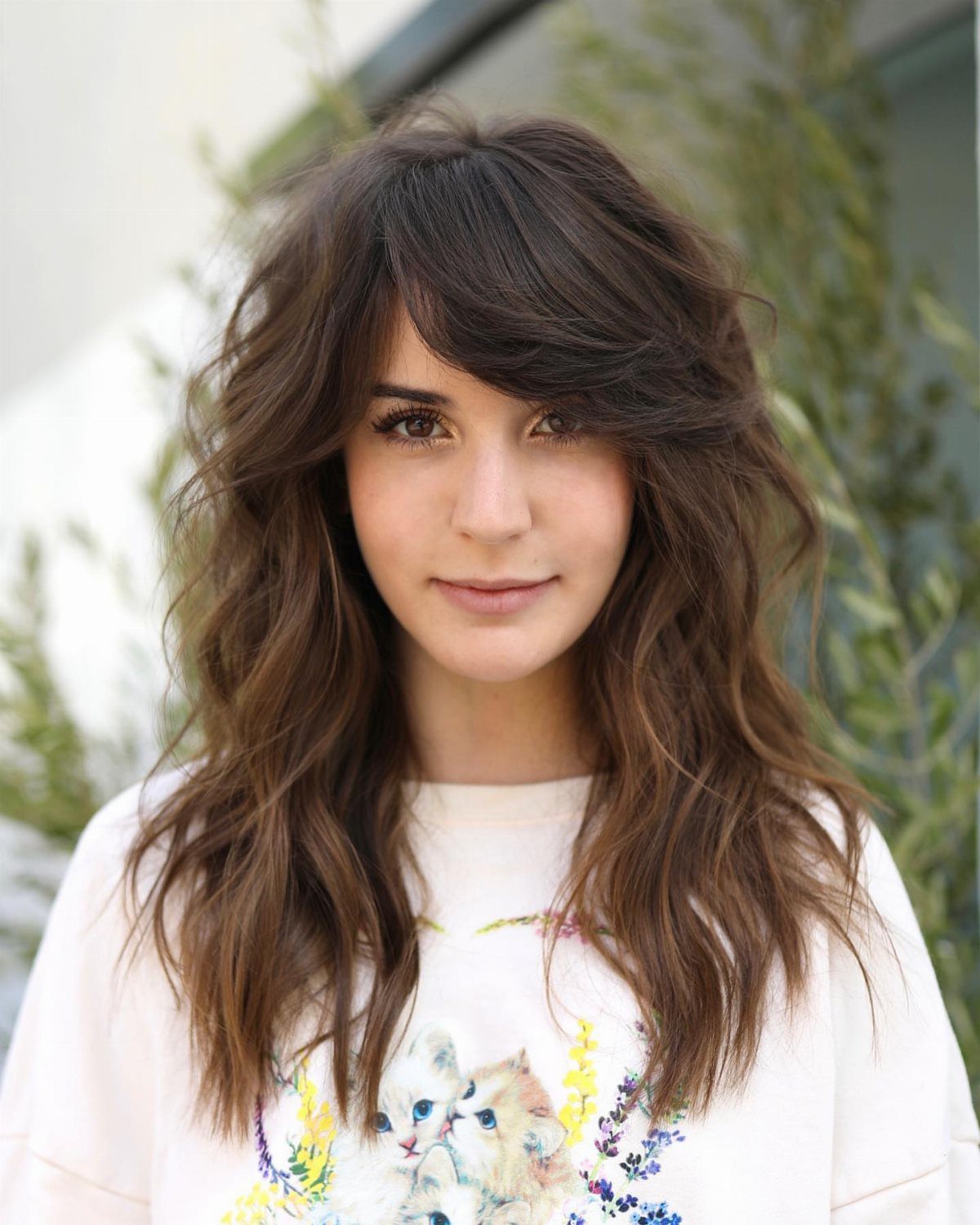 Woman with long dark hair and side-swept bangs partly covering one eye