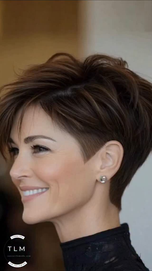 Woman showing a short, angular dark haircut with tapered sides and swept-back ends