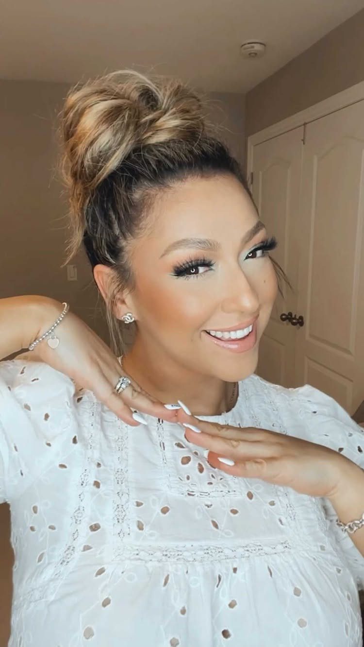 Woman posing with highlighted hair in a loose, high bun
