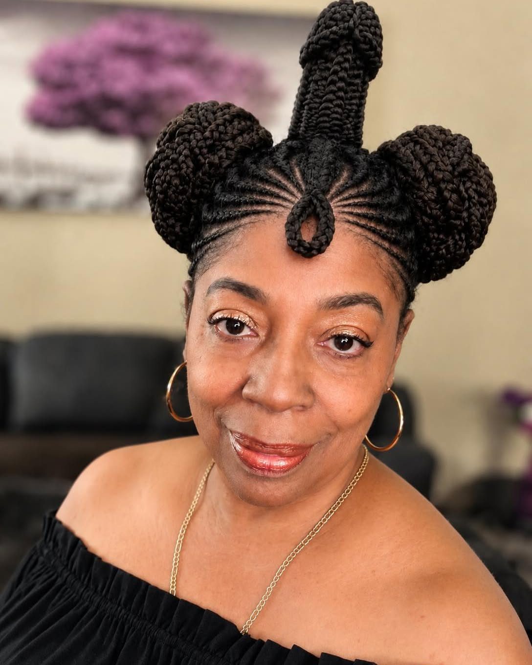 Woman wearing braided hair arranged into three rounded buns with a raised center bun