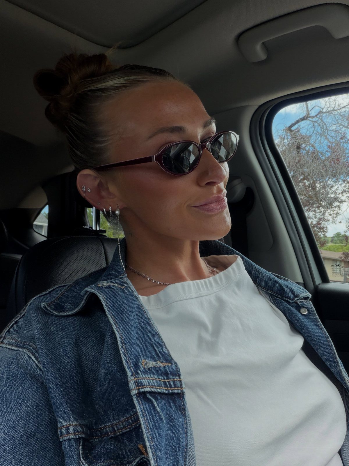 Woman with sleek hair pulled back into a bun, seated in a car