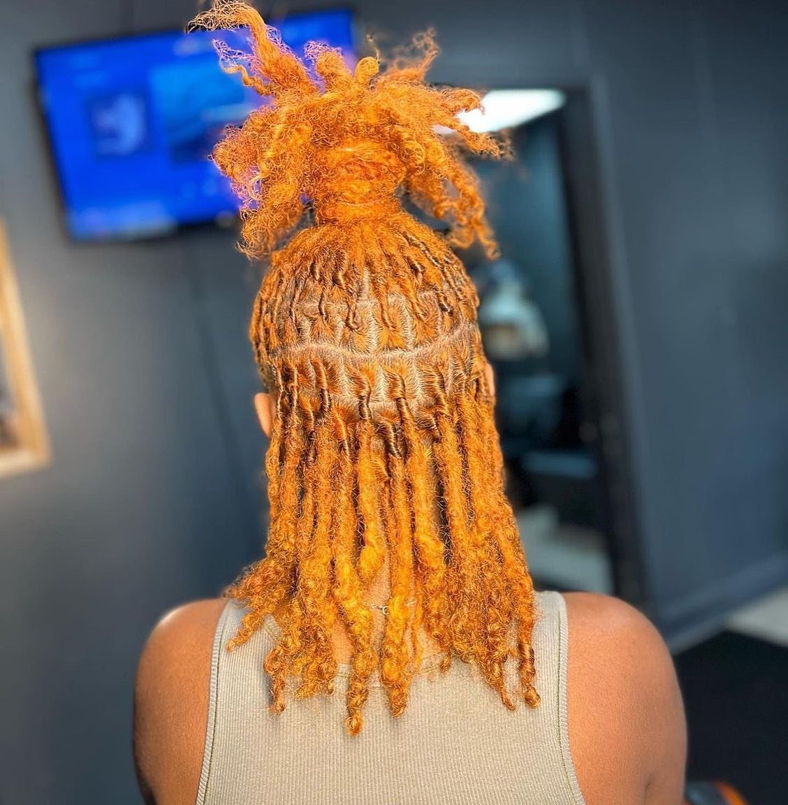 Orange locs gathered into a high bun with the rest hanging loose