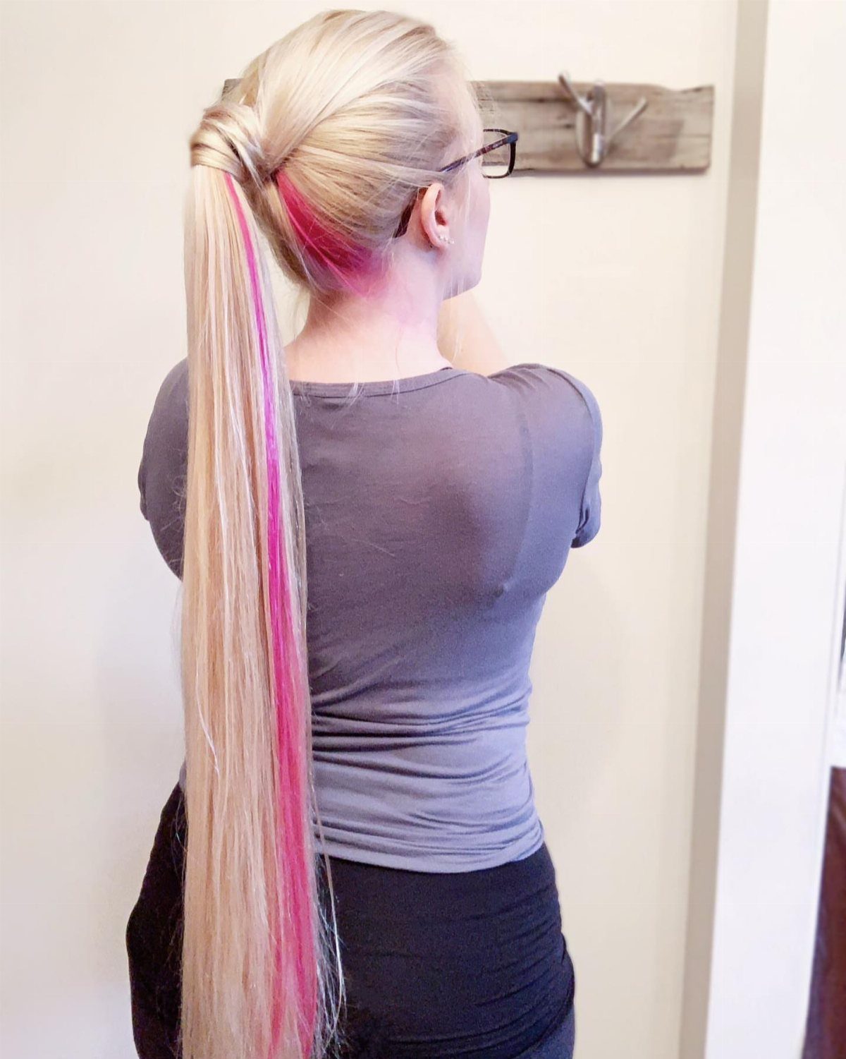 Long blonde ponytail with pink streaks hangs down the back of a woman