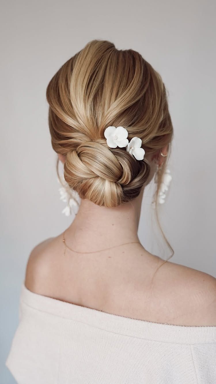 Blonde low chignon with white flowers, seen from behind