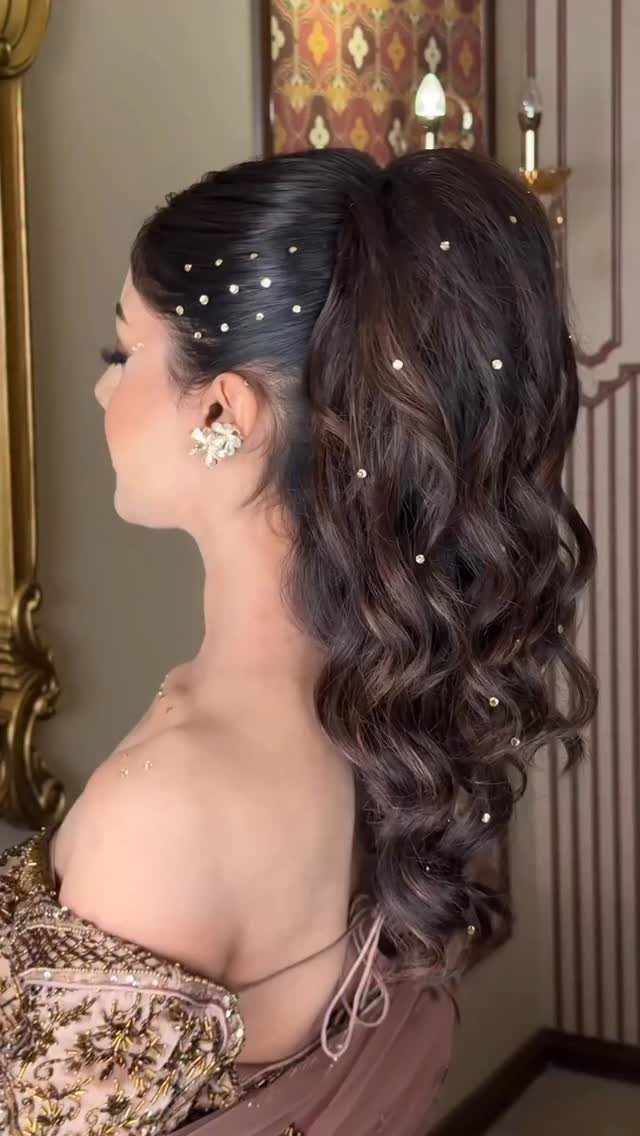High textured ponytail with long dark waves and small white hair ornaments