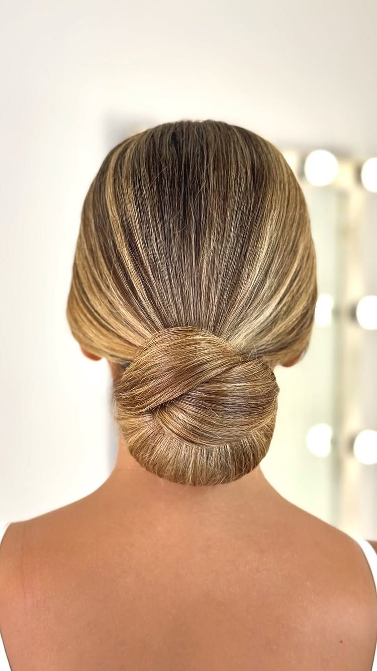 Blonde hair styled in a smooth low tucked ponytail roll