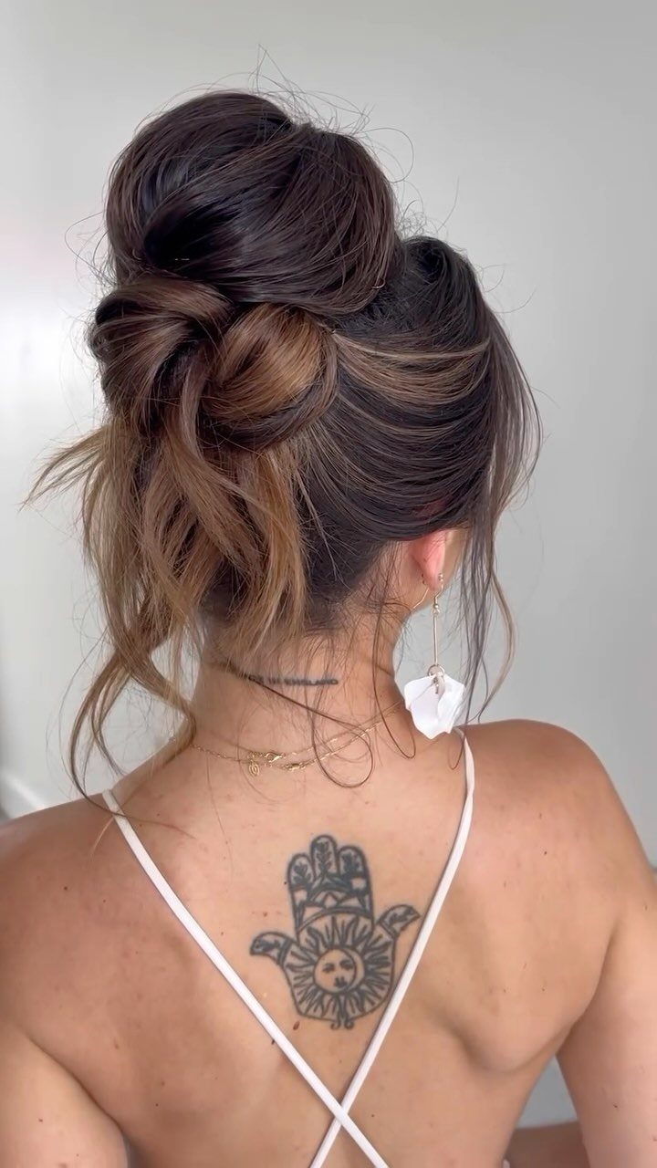 Twisted high bun with loose highlighted strands on a woman viewed from behind
