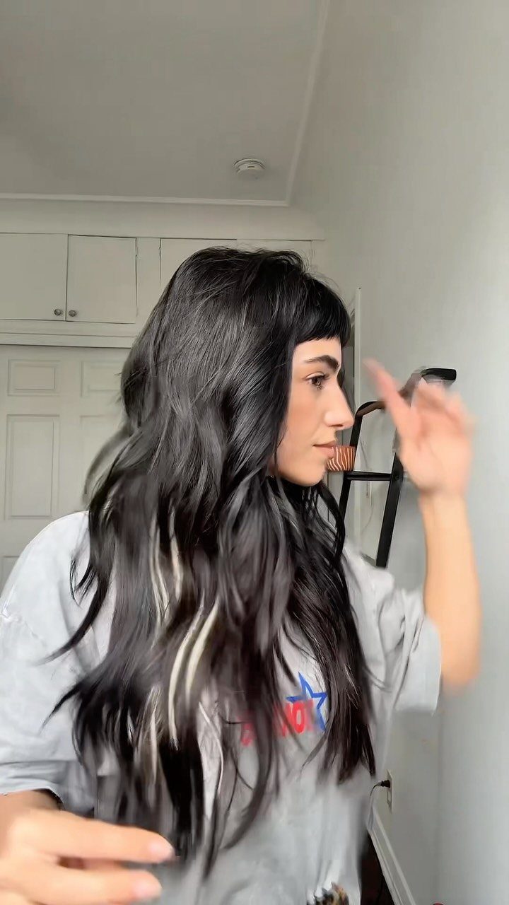 Long dark hair falls in loose, natural waves past a woman’s shoulders