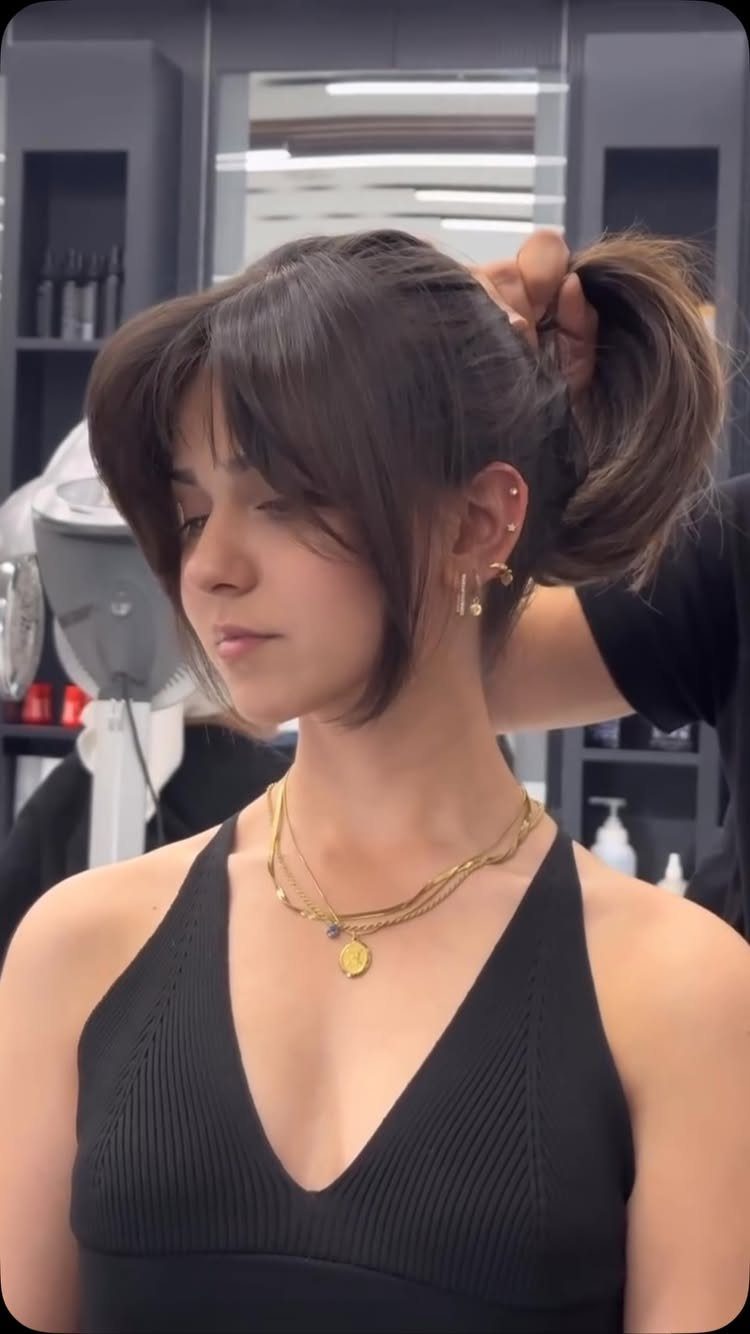 Woman with a chin-length dark bob and long curtain bangs in a salon