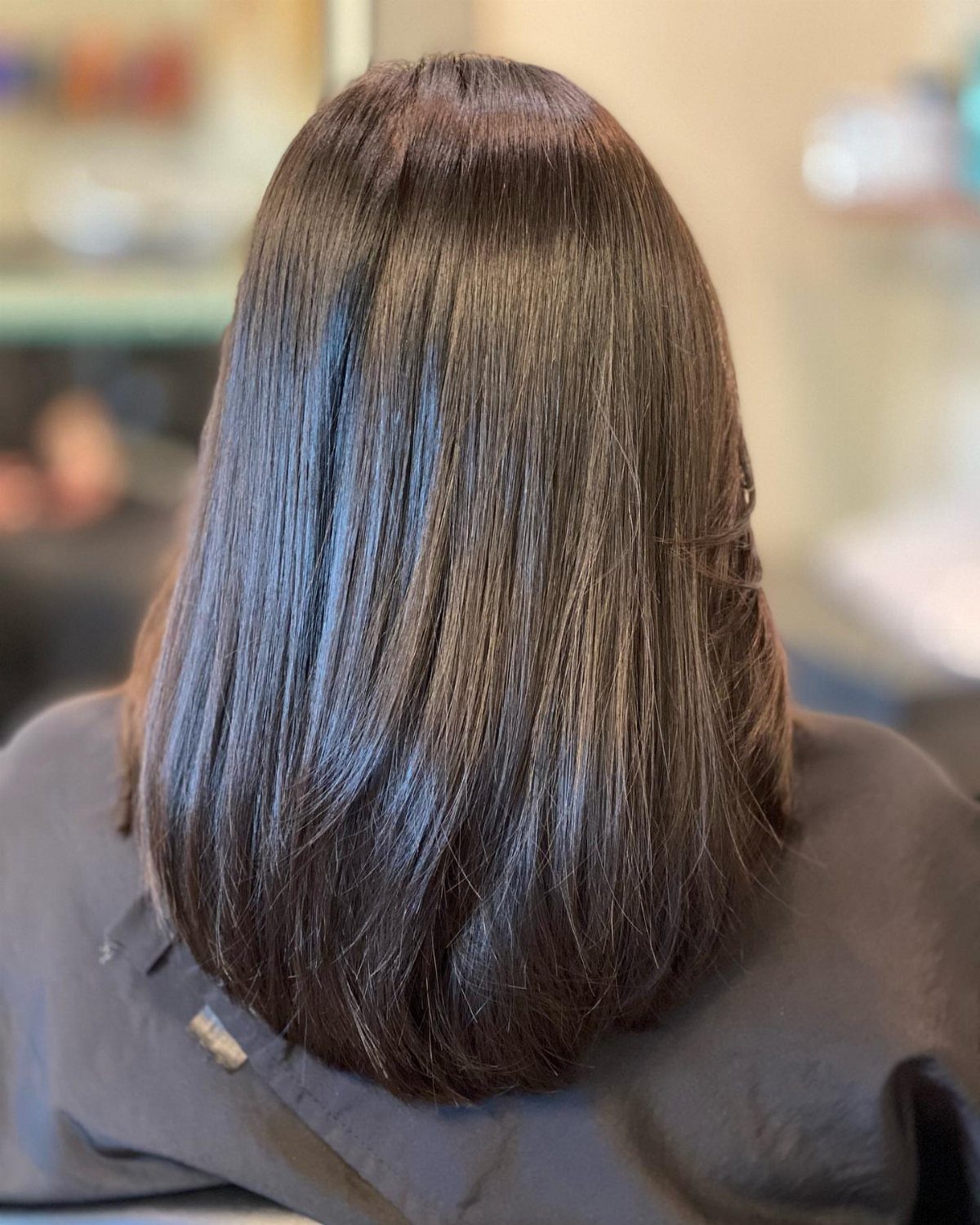 Long, glossy dark brown hair with ends forming a subtle U-shaped curve