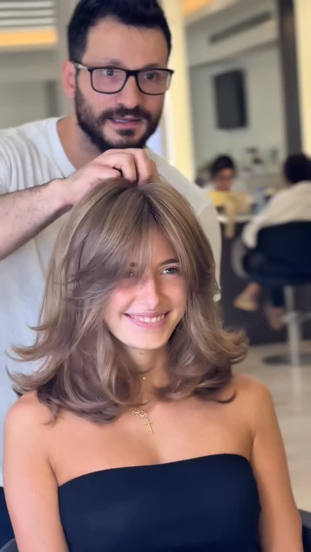 Woman shows shoulder-length butterfly layers with airy face-framing pieces and flipped ends