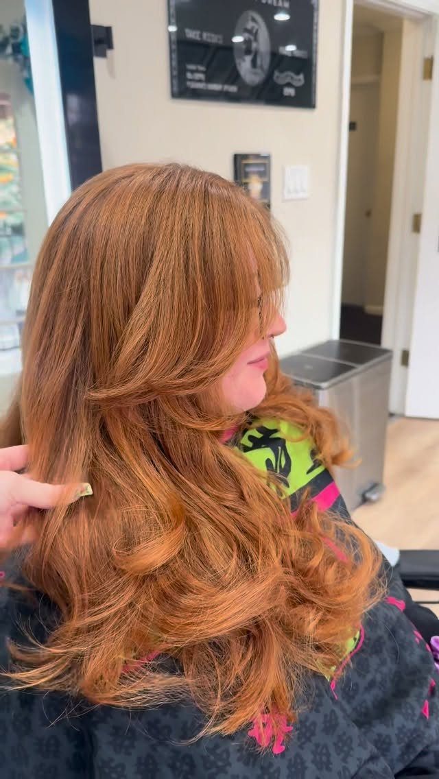 Copper-red layered hair with shorter face-framing pieces in a salon