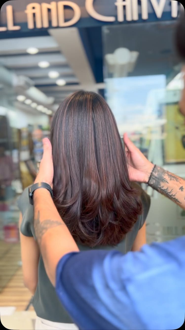 Straight dark shoulder-length hair with long layers displayed in a salon