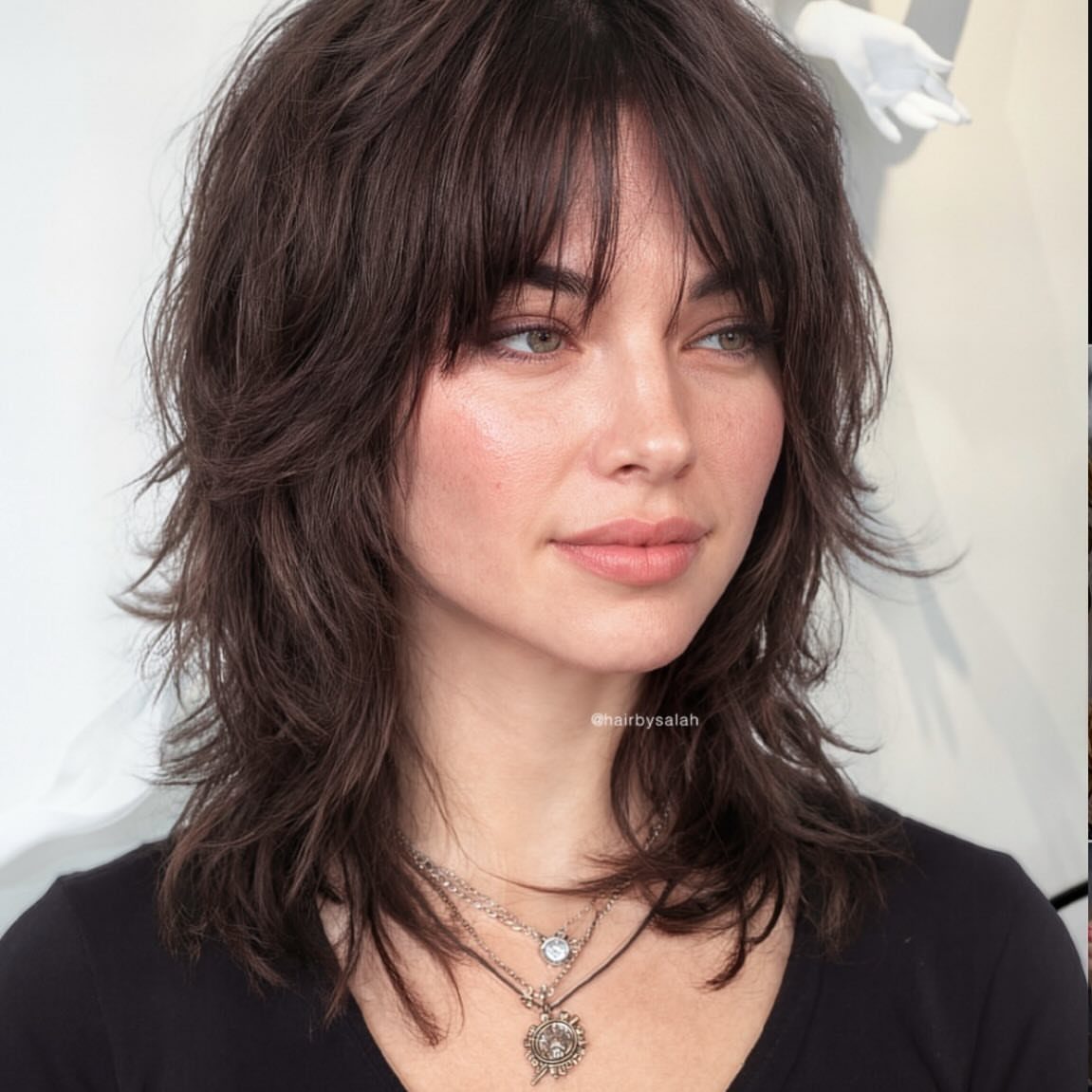 Woman wearing a dark, layered medium shag with choppy bangs