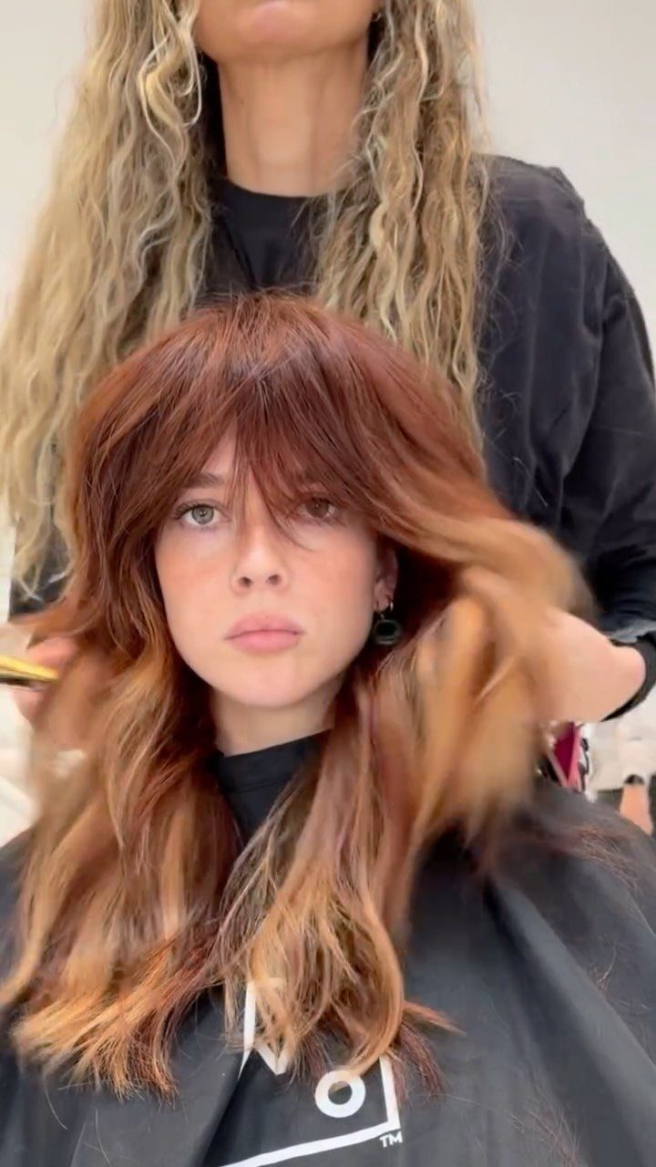 Copper-red shag haircut with thick bangs being styled at a salon