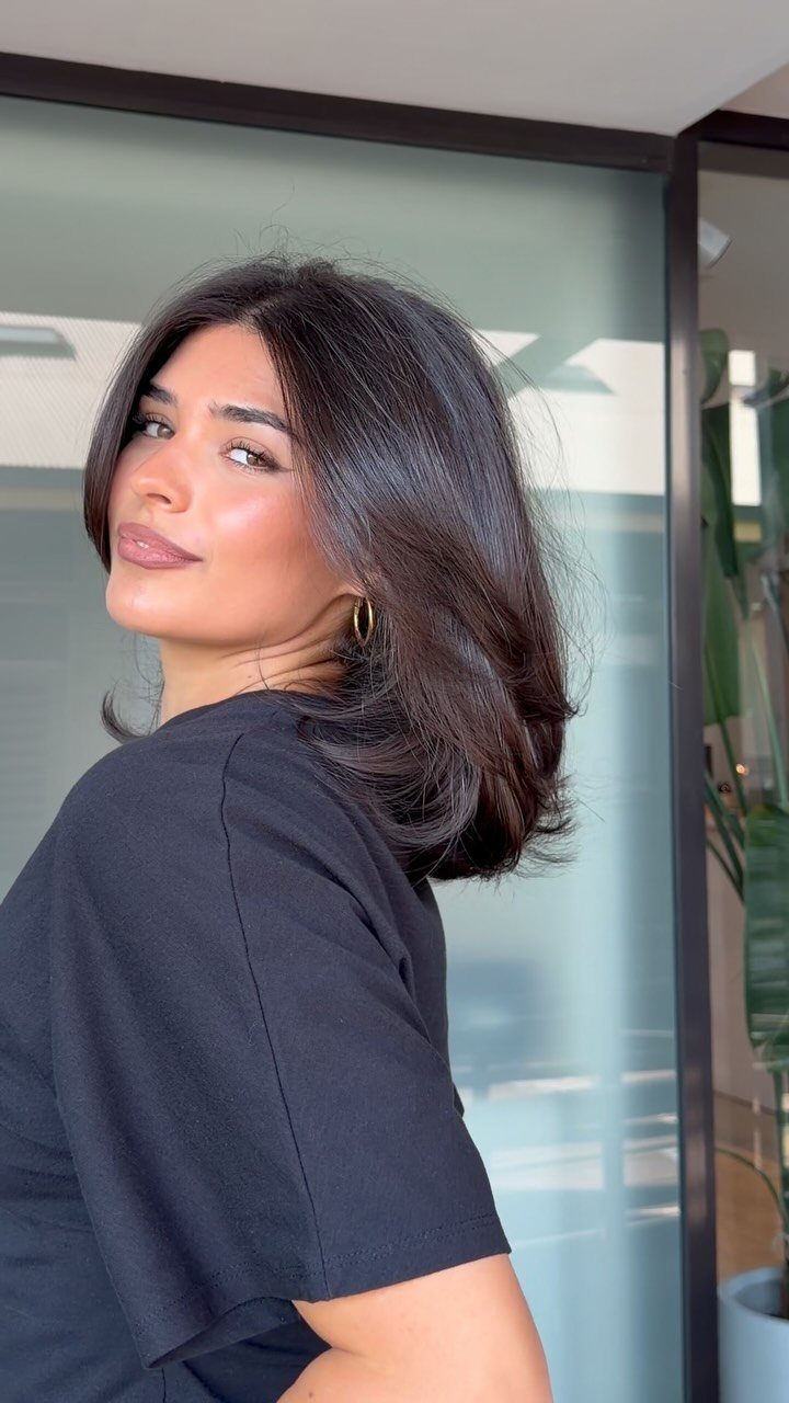 Woman showing a dark shoulder-length lob with soft layers and textured ends
