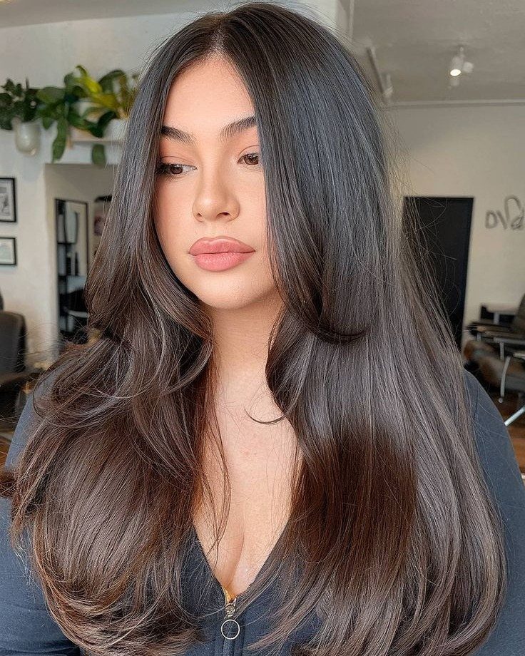 Woman with long dark layered hair curling softly under at the ends